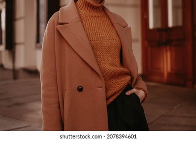 Cropped Female Figure In A Brown Cozy Warm Coat And Knitted Orange Sweater. Street Casual Winter Or Autumn Fashion.