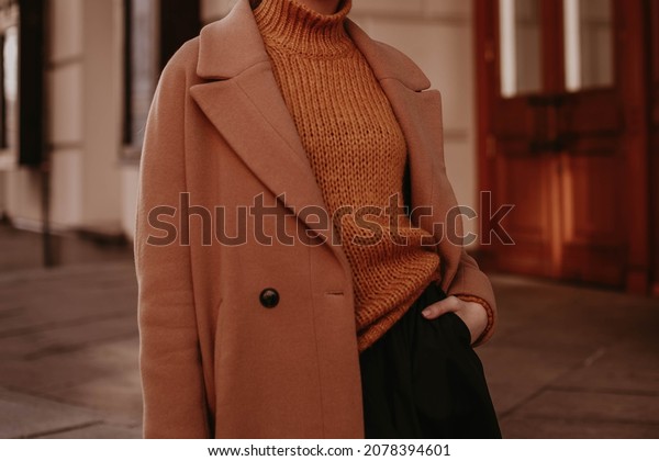 Cropped female\
figure in a brown cozy warm coat and knitted orange sweater. Street\
casual winter or autumn\
fashion.