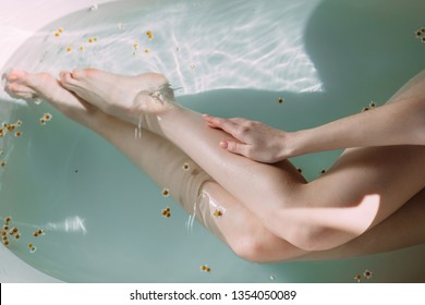 Cropped Female owner of slim long legs with white untanned skin taking bath during Spa treatment in hotel well-being area.