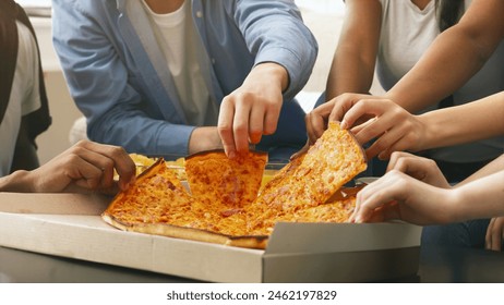 Cropped of group of friends are gathered around a table, eagerly reaching out to grab slices of a large pepperoni pizza from an open cardboard box during a casual social event - Powered by Shutterstock