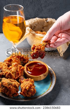 Cropped hand dipping fried chicken wing to bbq souse close up vertical photo. High quality photo