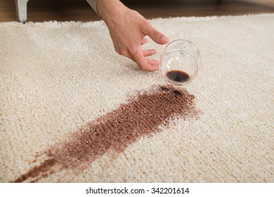 Cropped Hand Of Drunk Man Spilling Red Wine On Rug