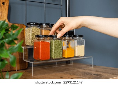 Cropped hand holding jar of spices on kitchen.