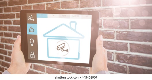 Cropped hand of man holding digital tablet against red brick wall