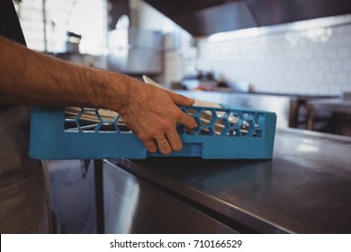 Cropped hand of waiter arranging plates in crate at commercial kitchen - Powered by Shutterstock