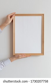 Cropped Hand Of Woman Holding Picture Frame Against Wall. Frame Mockup. 