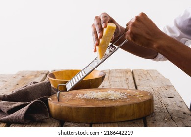 Cropped hands of african american chef grating cheese at table against white background, copy space. unaltered, food, preparation, studio shot and dairy product. - Powered by Shutterstock