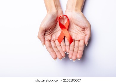 Cropped Hands Of African American Mid Adult Woman With Leukemia Awareness Ribbon On White Background. Copy Space, Orange, Leukemia, Cancer, Medical, Awareness, Support, Healthcare And Alertness.