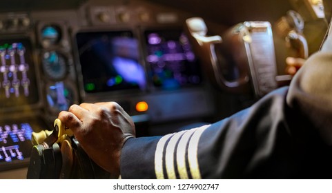 Cropped Hands of African Pilot flying a commercial airplane, cockpit view close up of hands