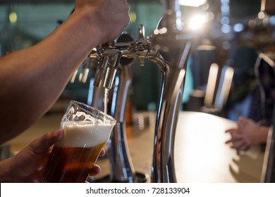 Cropped Hands Of Bartender Pouring Beer From Tap