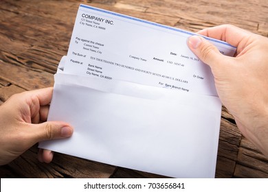 Cropped hands of businessman holding cheque at wooden table