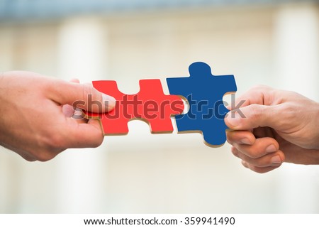 Cropped hands of businessmen joining jigsaw pieces outdoors