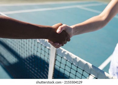 Cropped hands of female biracial tennis competitors with handshake over net at court on sunny day. unaltered, sport, competition and tennis game concept. - Powered by Shutterstock