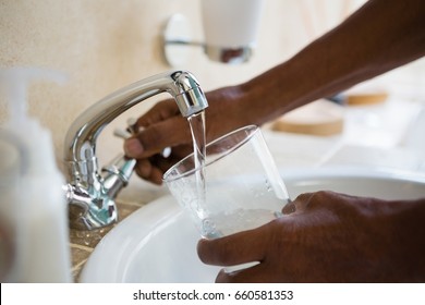 Cropped Hands Of Man Filling Water In Glass At Bathroom Sink