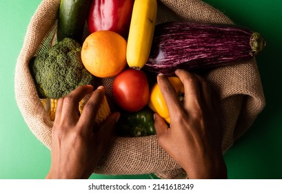 Cropped Hands Of Mixed Race Man Picking Up Vegetables From Burlap Sack. Unaltered, Food, Healthy Eating, Organic Concept.