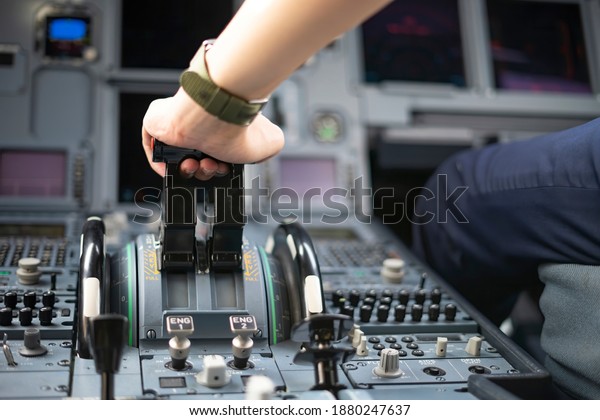 Cropped hands of pilot flying\
a commercial airplane, cockpit view close up of hands. Captain hand\
accelerating on the throttle in commercial airplane. Selective\
focus.