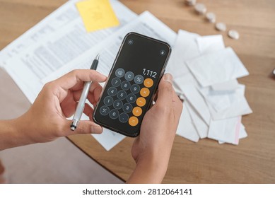 Cropped hands using calculator app on smartphone for tax planning
