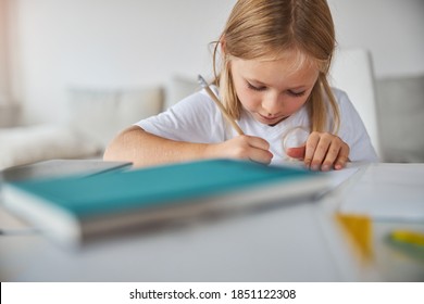 Cropped head portrait little charming cute girl in white shirt drawing something notebook while sitting at the desk