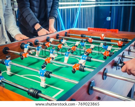 Cropped image of active people playing foosball. table soccer plaers. Friends play together table football