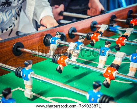 Cropped image of active people playing foosball. table soccer plaers. Friends play together table football