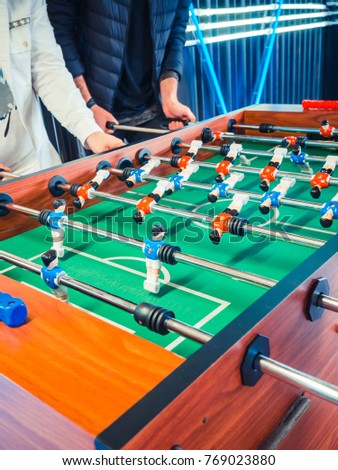 Cropped image of active people playing foosball. table soccer plaers. Friends play together table football