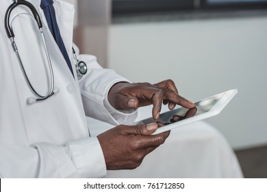 Cropped image of african american doctor searching something on a tablet