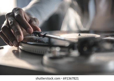 Cropped image african american man playing vinyl record at home