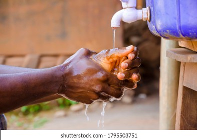 cropped image of an african washing his hands with soap and running tap water. - Powered by Shutterstock