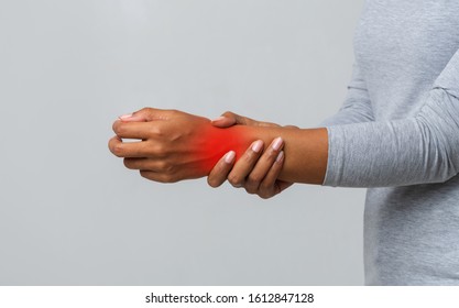 Cropped image of afro woman suffering from rheumatism, massaging her wrist, grey background
