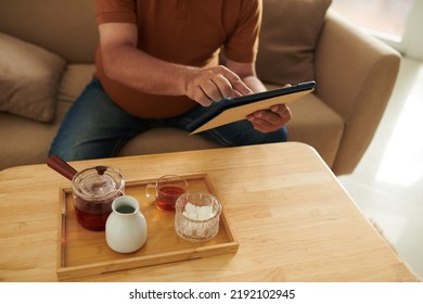 Cropped Image Of Aged Man Drinking Herbal Tea And Reading Articles On Digital Tablet At Home