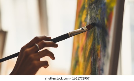 Cropped image of artist woman's hand drawing an oil color on canvas by paint brush at the modern art studio. Young artist/Painter concept. - Powered by Shutterstock