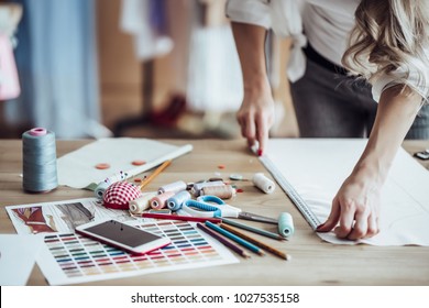 Cropped image of attractive female fashion designer is working in her workshop. Stylish woman in process of creating new clothes collection.