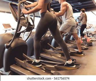 Cropped image of attractive young people working out on an elliptical trainer in gym - Powered by Shutterstock