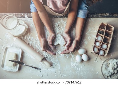 Cropped image of attractive young woman and her little cute daughter are cooking on kitchen. Having fun together while making cakes and cookies. Top view of mom with daughter making dough heart. - Shutterstock ID 739147612