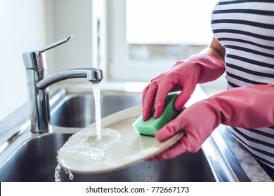 Cropped image of attractive young woman is washing dishes while doing cleaning at home - Shutterstock ID 772667173