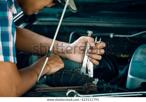 Cropped image of automobile mechanic repairing car\
in store, day time