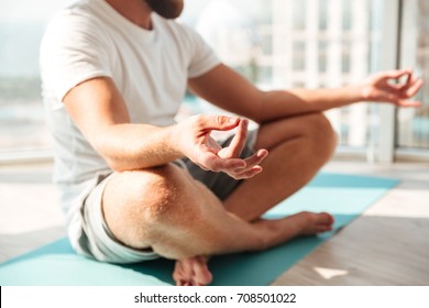 Cropped image of bearded man meditation over window background at home