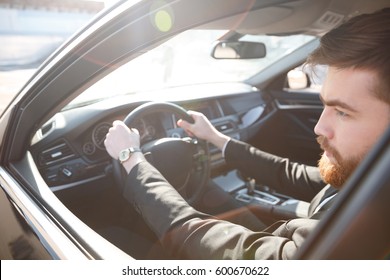 Cropped Image Of Bearded Man In Suit Driving Car And Looking Away