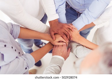Cropped image of beautiful business people in smart casual wear holding hands together