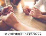 Cropped image of beautiful business team holding hands and praying while sitting in office