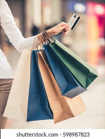 Cropped Image Of Beautiful Girl With Shopping Bags And Credit Card Doing Shopping In The Mall