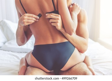 Cropped Image Of Beautiful Passionate Couple Having Sex On Bed. Man Is Unfastening Bra