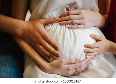 Cropped Image Of Beautiful Pregnant Woman, Her Husband And Child Holding Hand Together, Baby Inside. Love Of Family. Pregnancy, Preparation And Expectation Concept. Close Up.