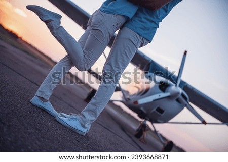 Cropped image of beautiful romantic couple hugging on take-off ground near the aircraft