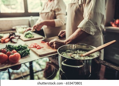 Cropped image of beautiful senior couple in aprons cooking together in kitchen - Powered by Shutterstock