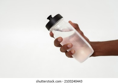 Cropped Image Of Black Man Holding Bottle With Water In Hand. Concept Of Healthy Lifestyle. Close Up. Isolated On White Background. Studio Shoot. Copy Space