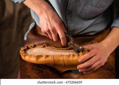 Cropped Image Of Bootmaker Sitting In Workshop Making Shoes