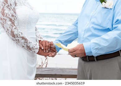 Cropped image of bride and groom sharing written vows