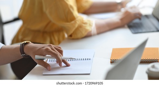 Cropped Image Of Business People Meeting With Computer Tablet And Laptop While Sitting Together At The Long White Table Over Comfortable Conference Room As Background.