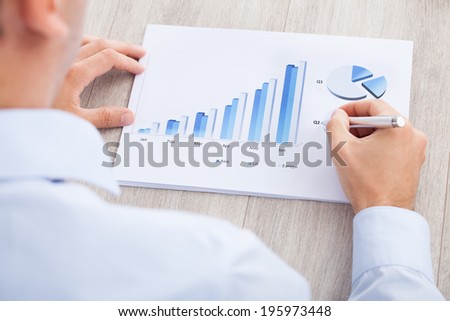 Cropped image of businessman analyzing graph at desk in office